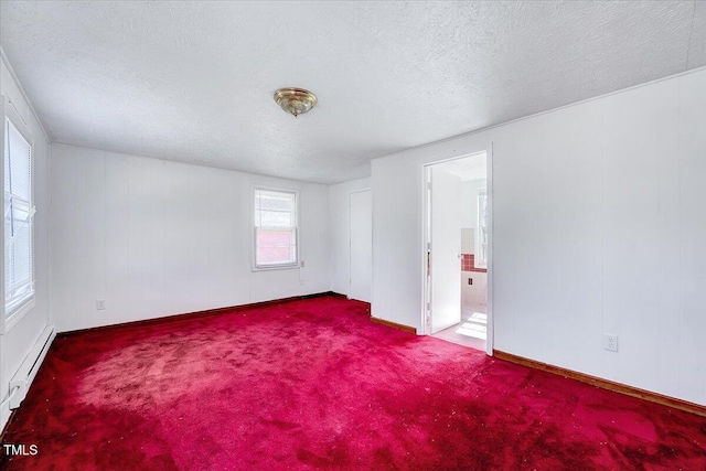 carpeted empty room featuring baseboard heating and a textured ceiling