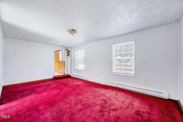 carpeted empty room featuring a baseboard heating unit and a textured ceiling