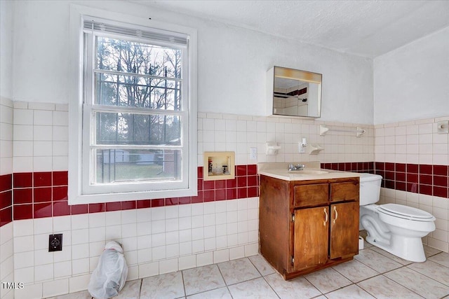 bathroom featuring tile walls, toilet, a textured ceiling, vanity, and tile patterned flooring