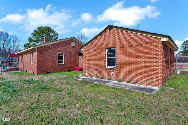 rear view of property featuring brick siding, fence, a yard, crawl space, and a chimney