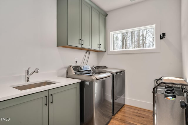 1124 Westridge Rd, Rougemont, NC 27572 - laundry area with baseboards, washing machine and clothes dryer, cabinet space, a sink, and light wood-type flooring