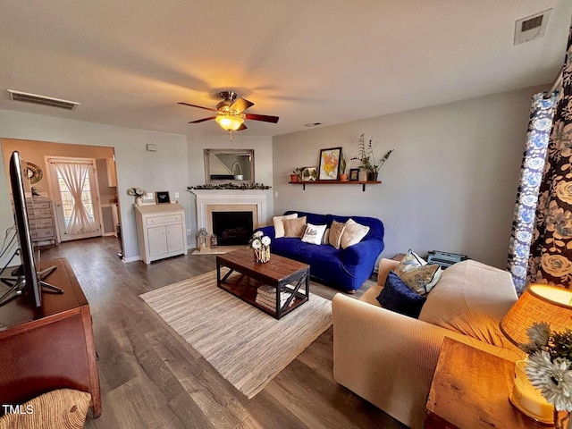 living area featuring dark wood-style floors, visible vents, a fireplace, and ceiling fan