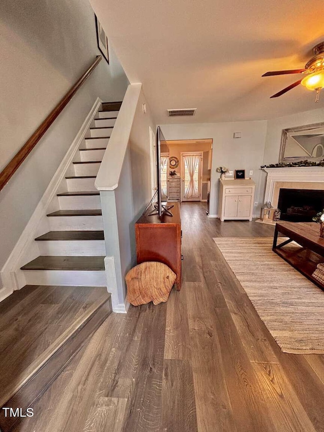 interior space featuring baseboards, visible vents, ceiling fan, wood finished floors, and a fireplace