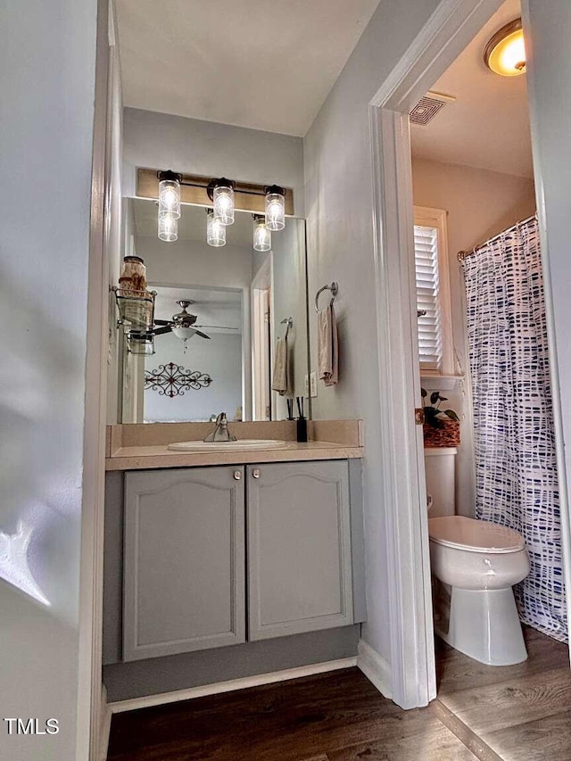 full bathroom with visible vents, toilet, ceiling fan, vanity, and wood finished floors