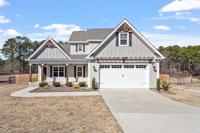 view of front of house with board and batten siding, covered porch, fence, and driveway