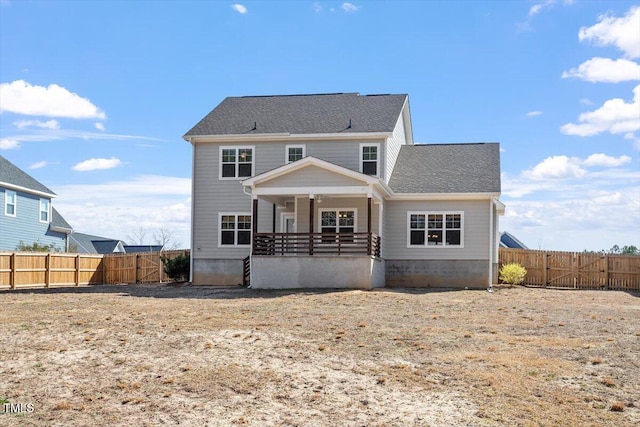 rear view of house featuring fence private yard and a porch