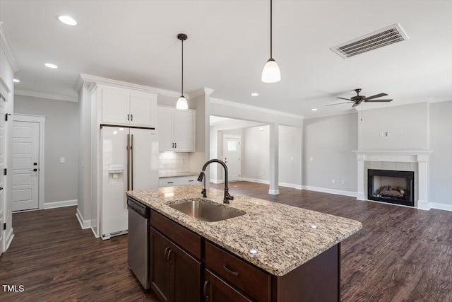 kitchen with white refrigerator with ice dispenser, crown molding, visible vents, stainless steel dishwasher, and a sink