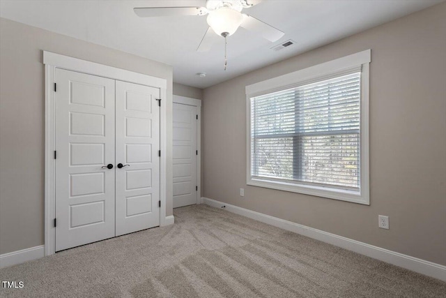 unfurnished bedroom featuring carpet floors, a ceiling fan, visible vents, baseboards, and a closet