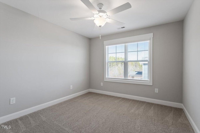 carpeted spare room featuring a ceiling fan and baseboards