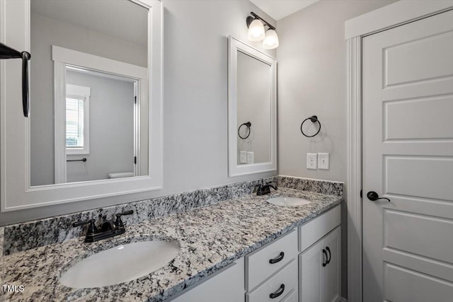 bathroom with double vanity, a sink, and toilet