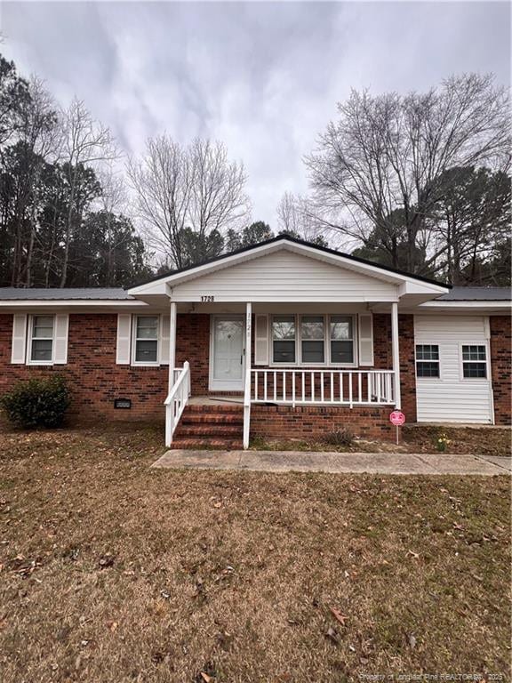 view of front facade with covered porch, brick siding, and a front lawn