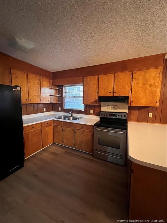 kitchen with dark wood-style floors, stainless steel electric range oven, freestanding refrigerator, under cabinet range hood, and a sink