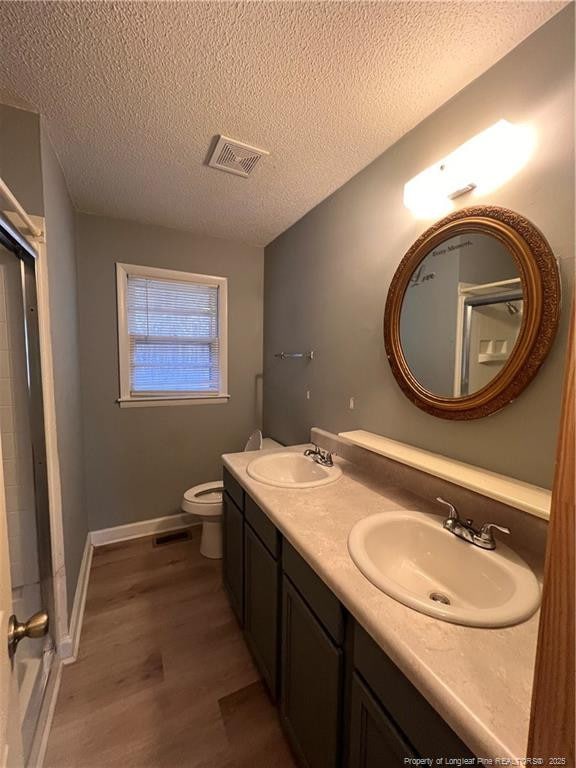 full bathroom with toilet, wood finished floors, a sink, and visible vents