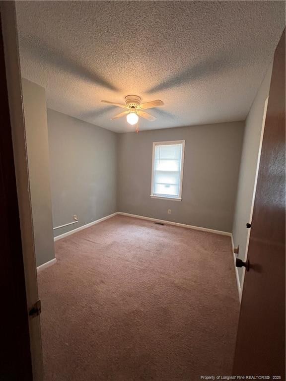 carpeted spare room featuring ceiling fan, a textured ceiling, and baseboards