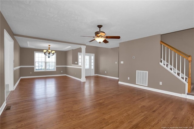 unfurnished living room featuring ceiling fan with notable chandelier, visible vents, stairway, and wood finished floors