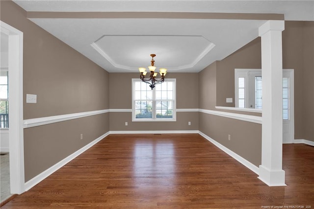 unfurnished dining area featuring a chandelier, a raised ceiling, baseboards, and wood finished floors