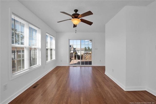 spare room featuring a ceiling fan, dark wood-style flooring, visible vents, and baseboards