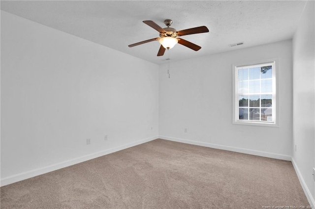 carpeted spare room featuring a textured ceiling, ceiling fan, visible vents, and baseboards