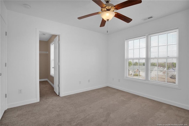 unfurnished bedroom with a spacious closet, carpet, visible vents, and baseboards