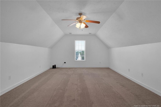 bonus room with carpet flooring, vaulted ceiling, a textured ceiling, ceiling fan, and baseboards