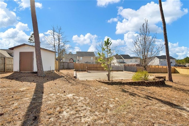 view of yard featuring an outbuilding, a patio area, a fenced backyard, and a residential view