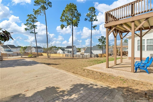 view of yard with a deck, a patio area, fence, and a residential view