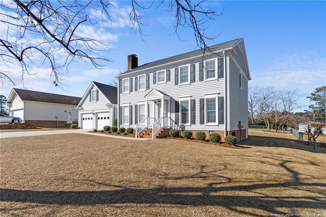 colonial-style house featuring a garage, driveway, crawl space, a front lawn, and a chimney