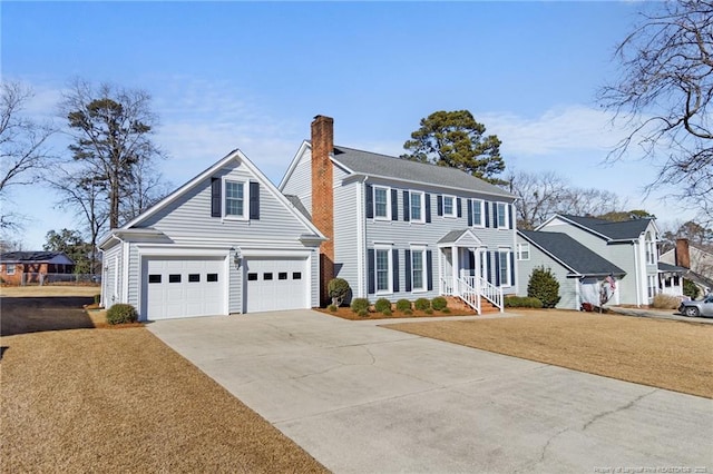 colonial house featuring a garage, a front yard, driveway, and a chimney