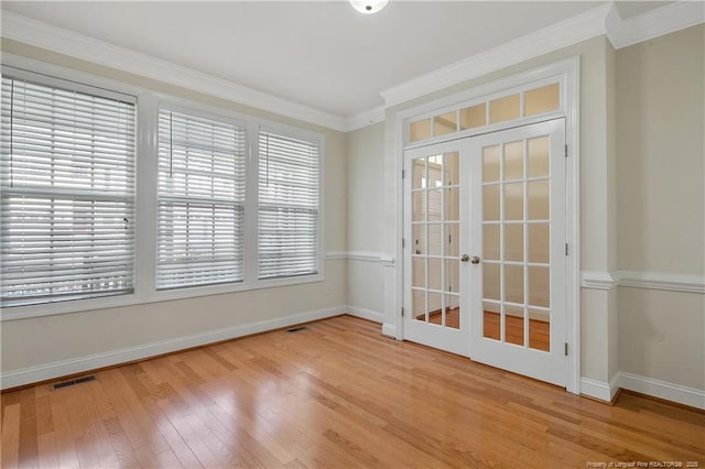 spare room with wood finished floors, visible vents, baseboards, french doors, and ornamental molding