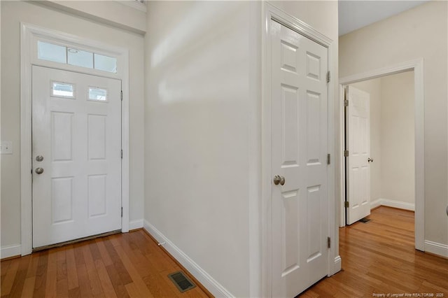 foyer with light wood-style floors, visible vents, and baseboards