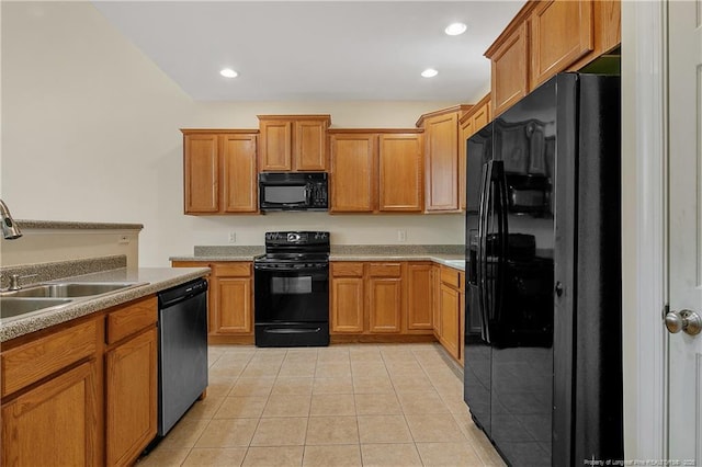 kitchen with black appliances, light tile patterned floors, brown cabinetry, and a sink