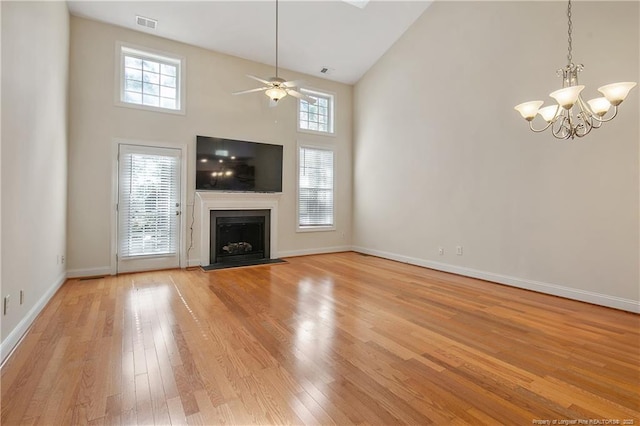 unfurnished living room with high vaulted ceiling, light wood-style flooring, a fireplace, visible vents, and baseboards