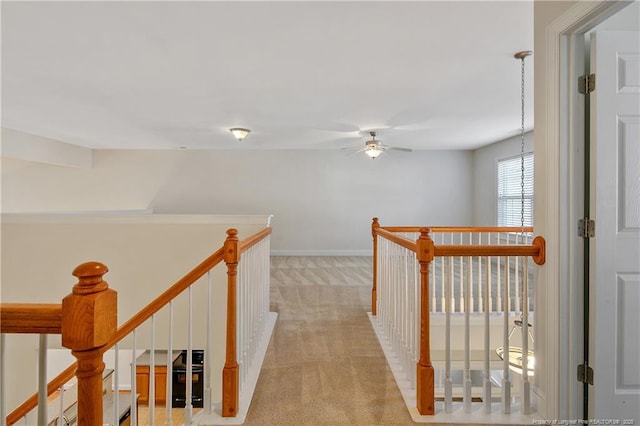 hallway with light carpet, baseboards, and an upstairs landing