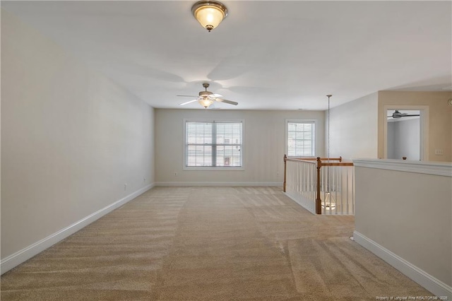 spare room featuring light colored carpet and baseboards