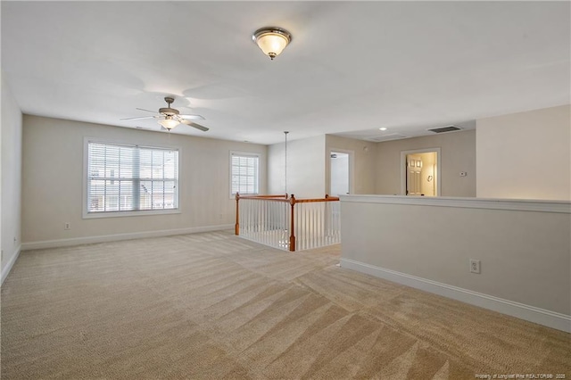 empty room with visible vents, baseboards, ceiling fan, and light colored carpet