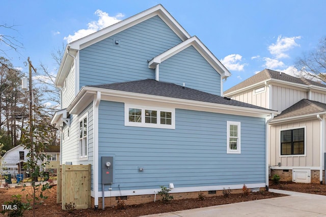 view of side of home with crawl space and a shingled roof