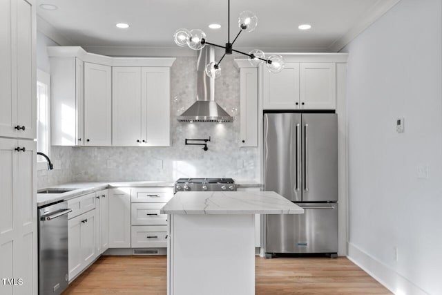 kitchen with white cabinetry, wall chimney exhaust hood, appliances with stainless steel finishes, and a sink