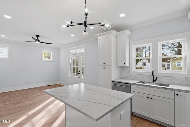 kitchen with a sink, tasteful backsplash, stainless steel dishwasher, and ornamental molding