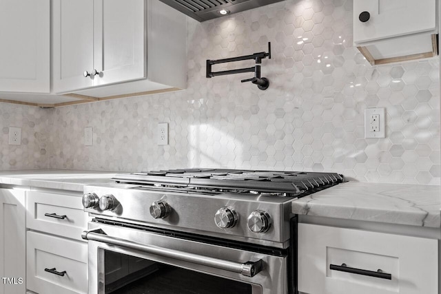 kitchen with backsplash, ventilation hood, light stone countertops, high end stainless steel range oven, and white cabinets