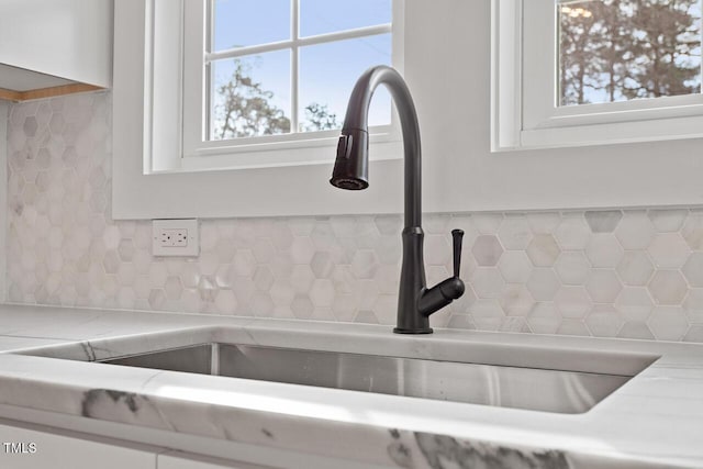 interior details featuring a sink, tasteful backsplash, white cabinets, and light countertops