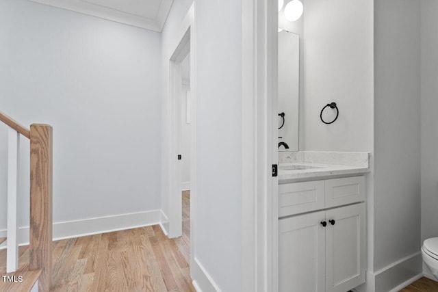 bathroom featuring baseboards, toilet, wood finished floors, and vanity