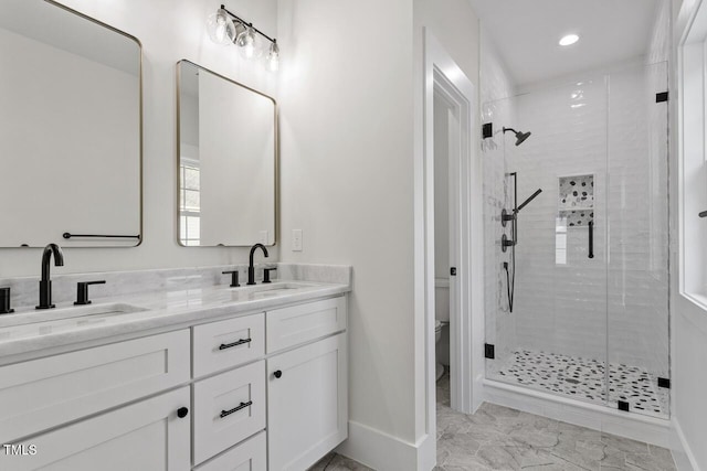 full bathroom featuring double vanity, toilet, a stall shower, and a sink