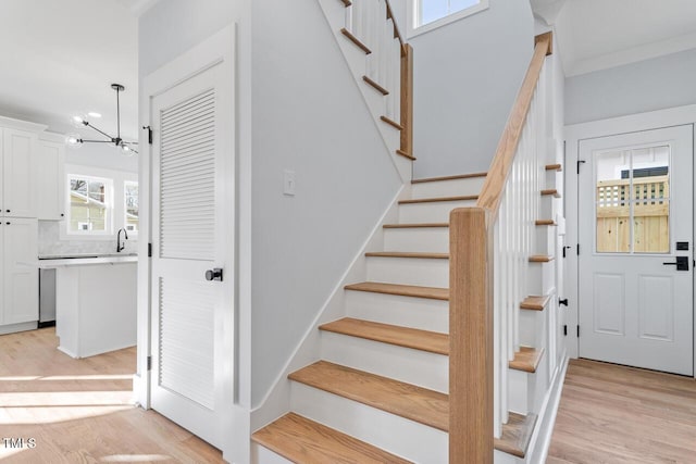 stairway with an inviting chandelier and wood finished floors