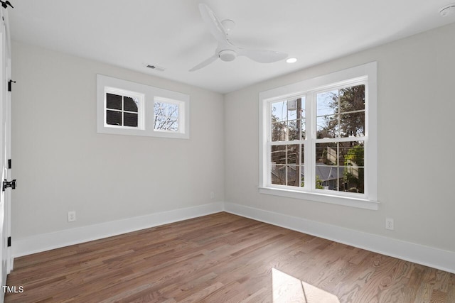 empty room featuring visible vents, ceiling fan, baseboards, and wood finished floors