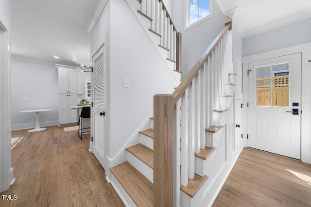 foyer entrance featuring stairway, recessed lighting, ornamental molding, and light wood-type flooring
