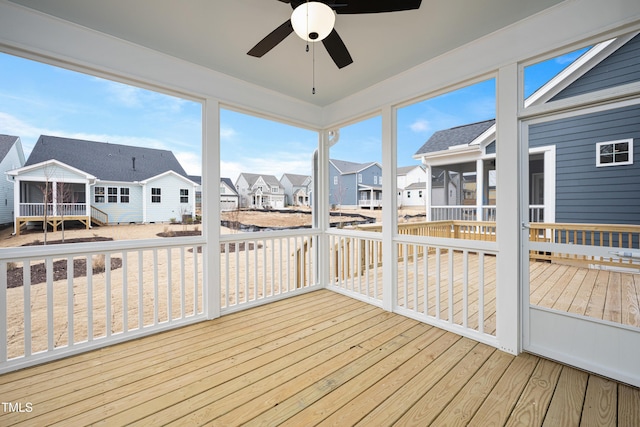 unfurnished sunroom with a healthy amount of sunlight, a residential view, and a ceiling fan