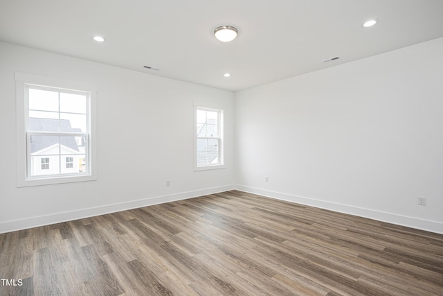 empty room with recessed lighting, wood finished floors, visible vents, and baseboards