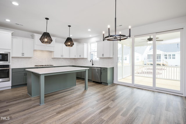 kitchen featuring gray cabinetry, stainless steel appliances, light wood-style floors, light countertops, and tasteful backsplash