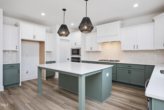 kitchen featuring wood finished floors, light countertops, appliances with stainless steel finishes, and a kitchen island