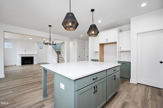 kitchen with a fireplace, recessed lighting, light countertops, white cabinets, and light wood-type flooring